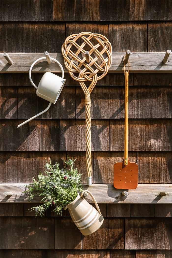 Heritage Rattan Rug Beater — rug beater hanging on a wooden wall; Farmhouse Pottery