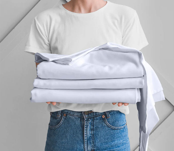 Night Song Sheet Set by City Mattress, model holding white sheets