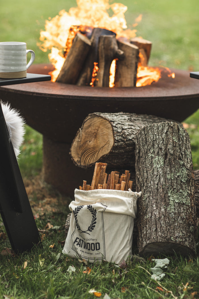 Pine Fatwood Fire Starter — fatwood bag beside a fire pit and logs; Farmhouse Pottery
